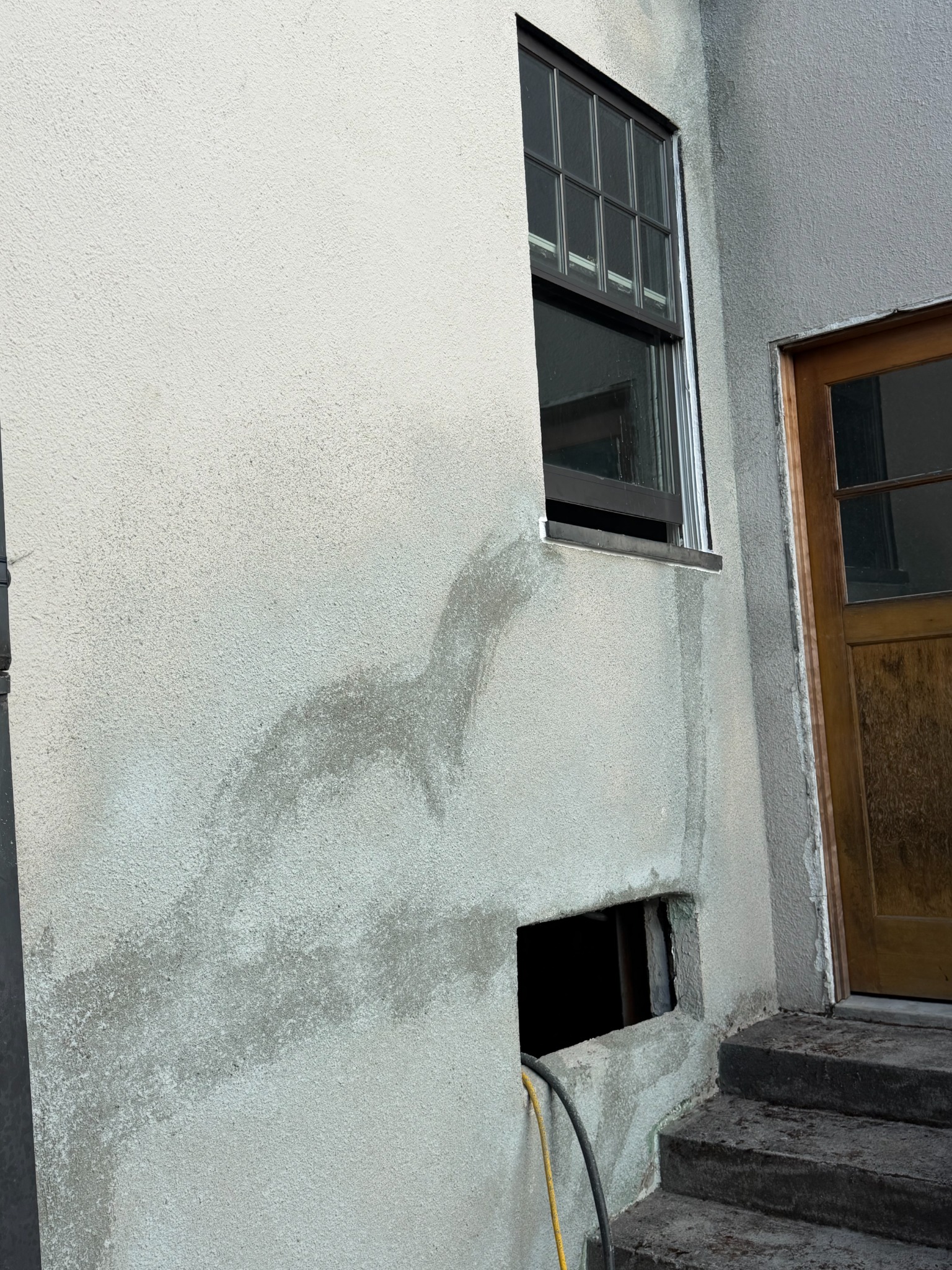 After stucco repair: wall surface beside the wood entry door and steps