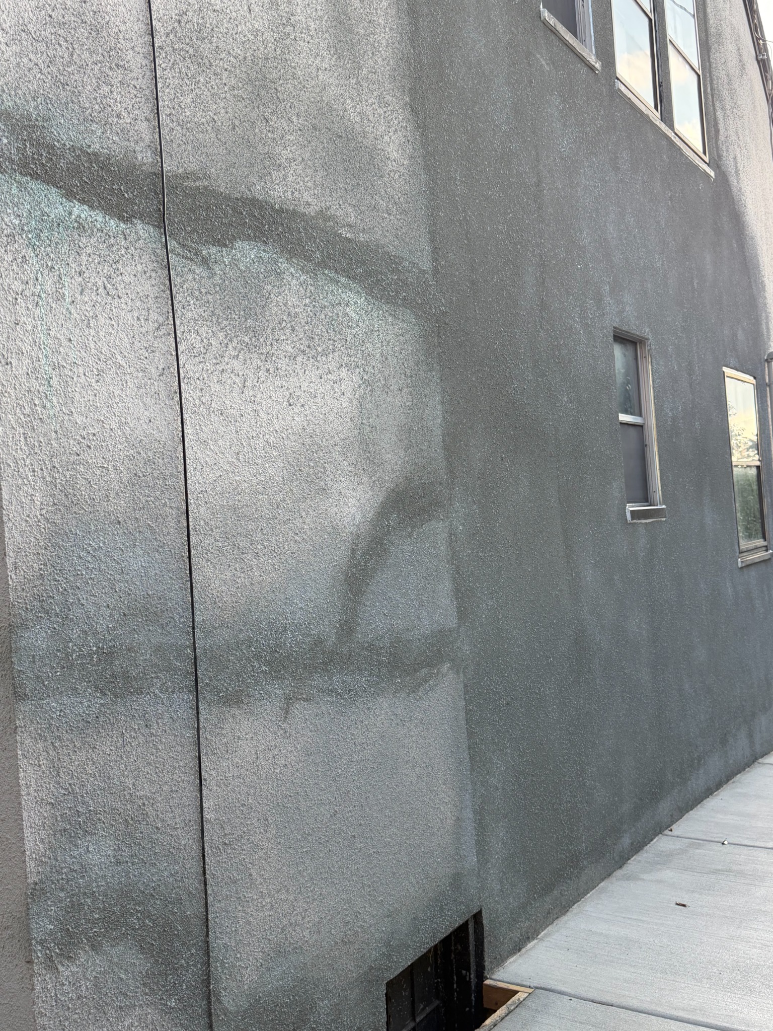 After stucco repair: textured exterior wall beside the concrete walkway
