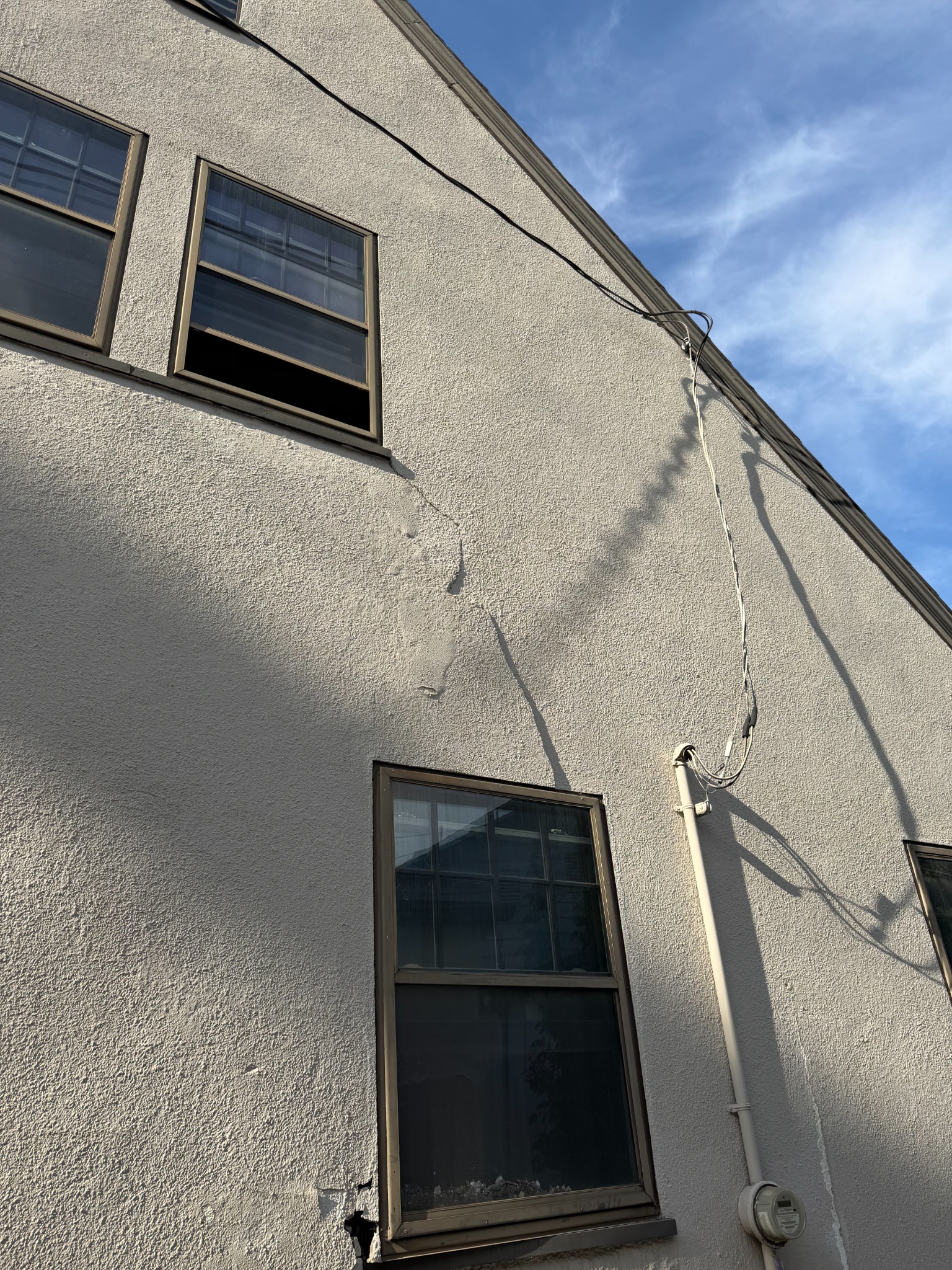 Before repair: wider view of cracked stucco across the exterior wall